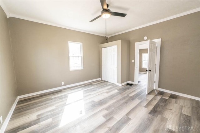 empty room with crown molding, baseboards, ceiling fan, and wood finished floors