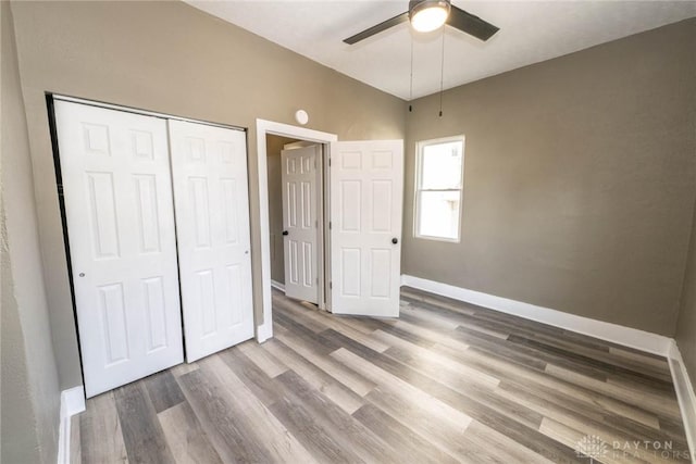 unfurnished bedroom with a ceiling fan, baseboards, wood finished floors, and a closet