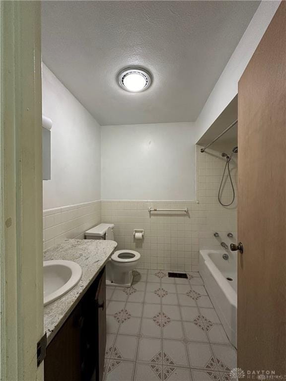 bathroom with wainscoting, tile walls, vanity, and toilet