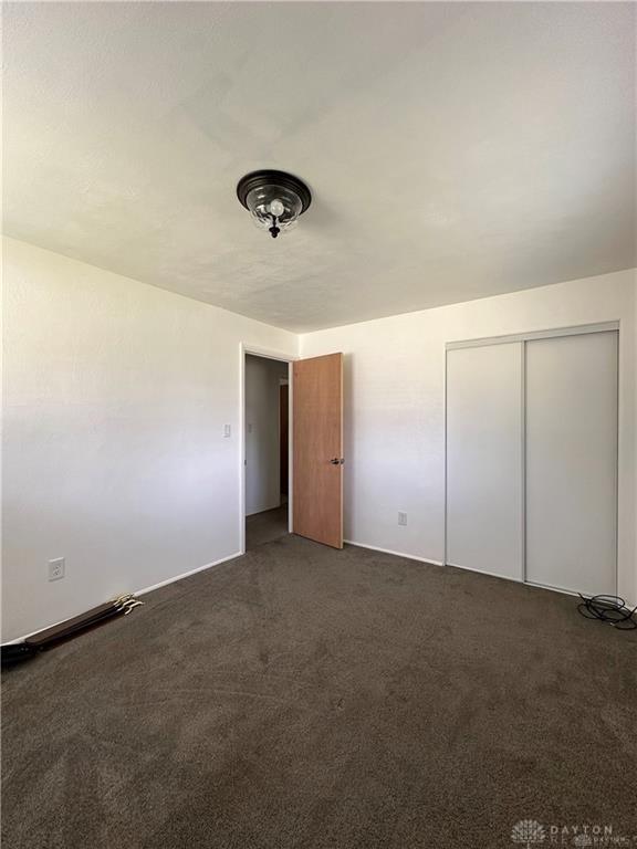 unfurnished bedroom featuring baseboards, carpet, and a closet