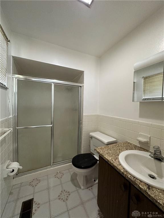 full bath with vanity, wainscoting, toilet, tile walls, and a shower stall
