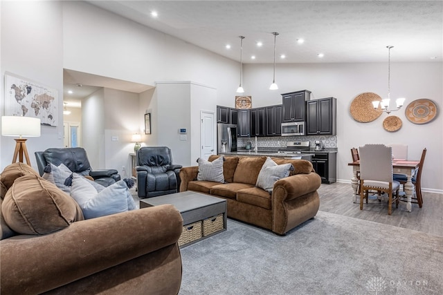 living area featuring an inviting chandelier, light wood-style floors, baseboards, high vaulted ceiling, and recessed lighting