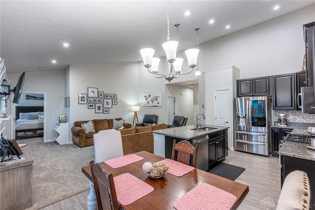 dining space with light wood-style floors, recessed lighting, a high ceiling, and a chandelier