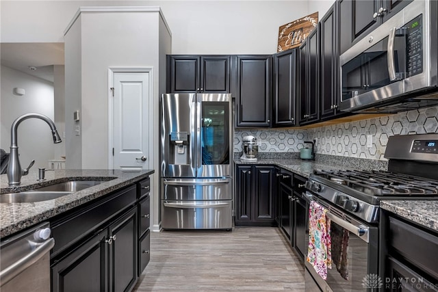 kitchen featuring a sink, dark cabinets, stainless steel appliances, and dark stone countertops