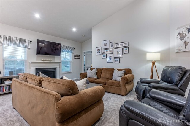 living room featuring high vaulted ceiling, a fireplace, recessed lighting, and light colored carpet