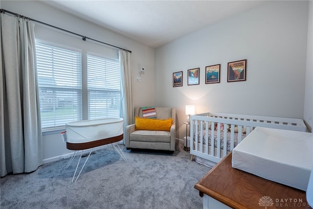 carpeted bedroom with baseboards and a crib