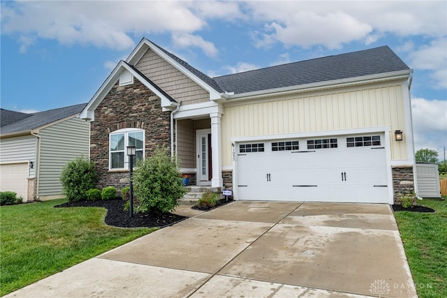 craftsman-style house with a garage, concrete driveway, a front yard, and stone siding