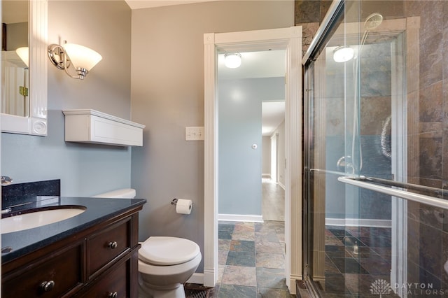 bathroom featuring vanity, baseboards, a stall shower, and toilet
