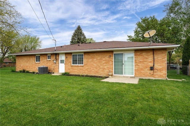 back of house featuring a yard, brick siding, fence, and central air condition unit