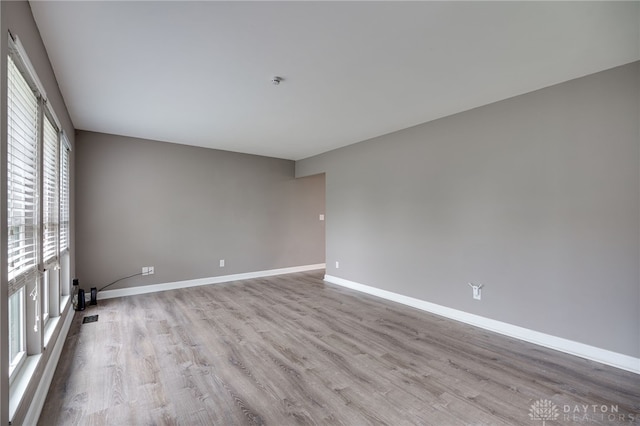 empty room featuring baseboards, wood finished floors, and visible vents