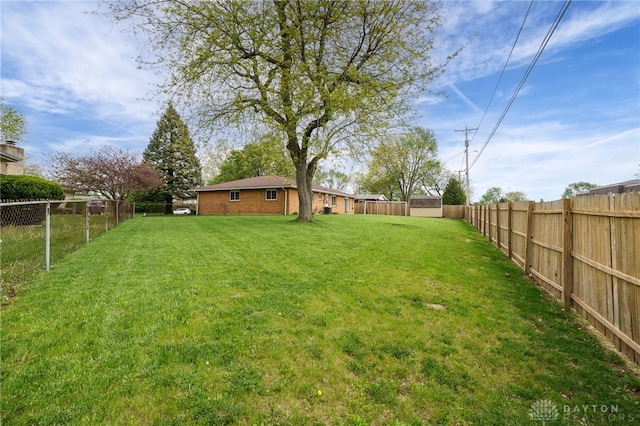 view of yard featuring a storage unit, a fenced backyard, and an outbuilding