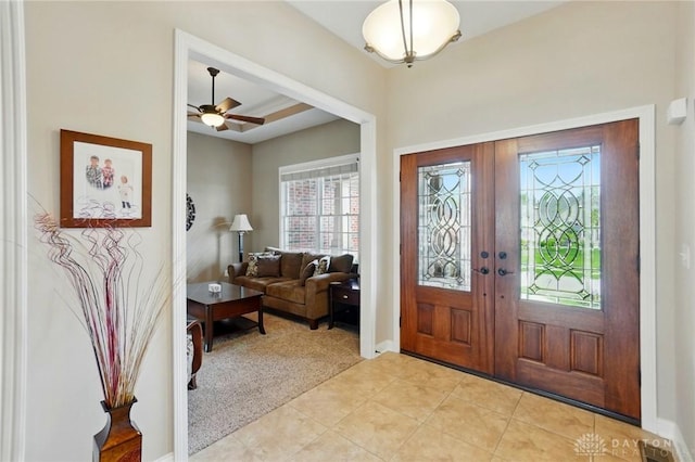 foyer with baseboards, light colored carpet, french doors, a ceiling fan, and light tile patterned floors