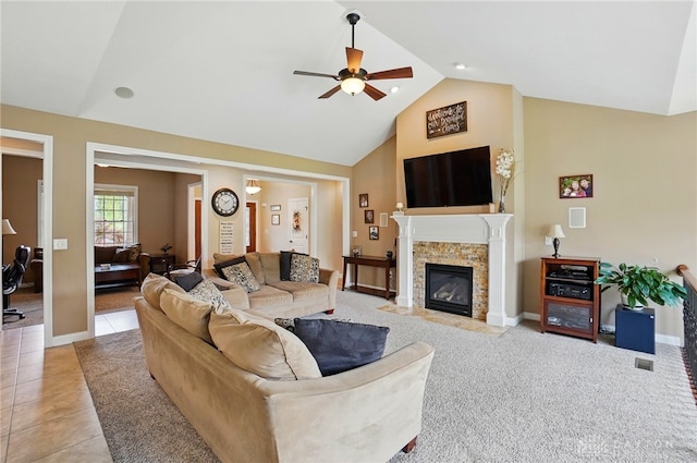 living area featuring baseboards, high vaulted ceiling, a tiled fireplace, a ceiling fan, and light tile patterned floors