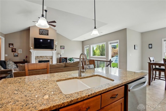 kitchen featuring brown cabinetry, a ceiling fan, open floor plan, a sink, and hanging light fixtures