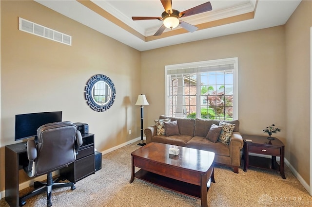 home office with light colored carpet, ceiling fan, visible vents, and a tray ceiling