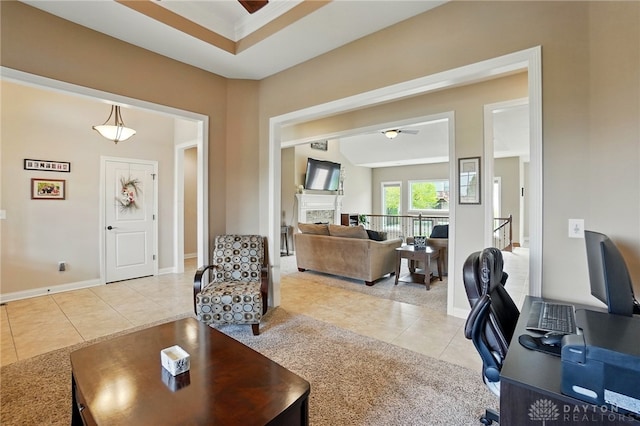 living area featuring baseboards, ceiling fan, light tile patterned floors, and a fireplace