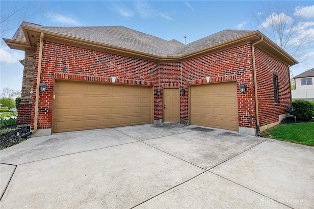 exterior space with concrete driveway, brick siding, a shingled roof, and a garage