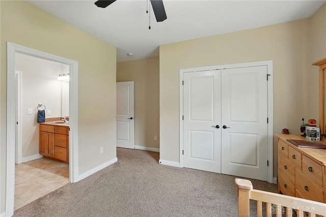 bedroom with connected bathroom, light carpet, a ceiling fan, baseboards, and a closet