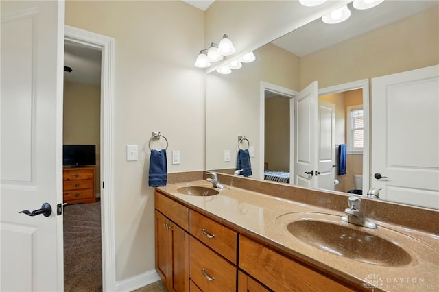 ensuite bathroom with double vanity, a sink, ensuite bath, and toilet