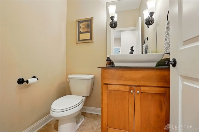 half bath with vanity, baseboards, tile patterned flooring, and toilet
