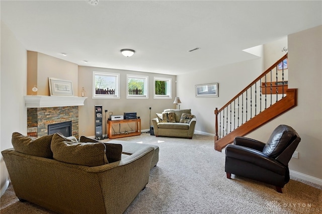 living area featuring a stone fireplace, carpet, baseboards, and stairway