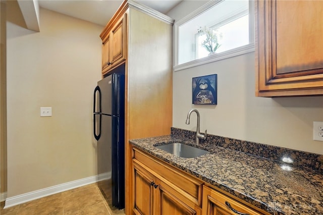 kitchen with freestanding refrigerator, brown cabinets, baseboards, and a sink