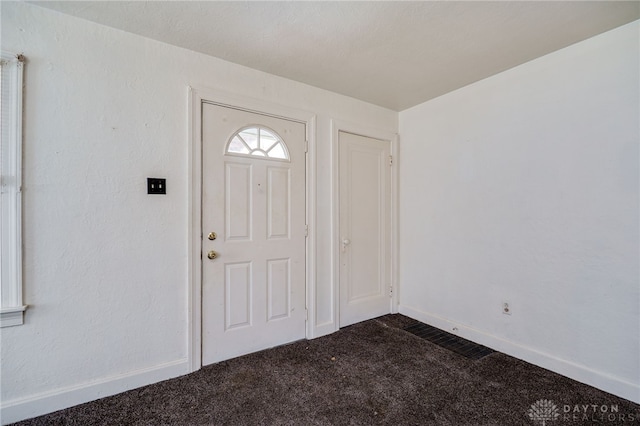 entrance foyer with baseboards and dark carpet
