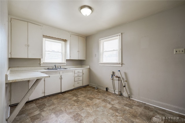 kitchen with a sink, light countertops, plenty of natural light, and white cabinetry