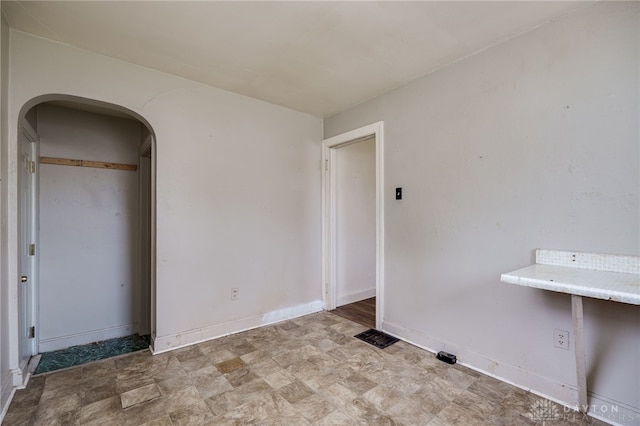 unfurnished room featuring arched walkways, baseboards, and visible vents