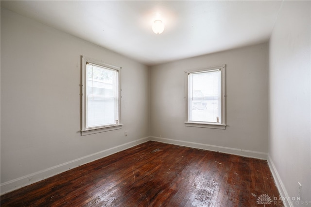 empty room featuring baseboards, plenty of natural light, and hardwood / wood-style floors