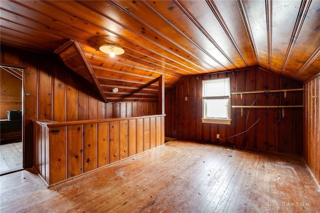 additional living space with wooden walls, hardwood / wood-style flooring, and lofted ceiling
