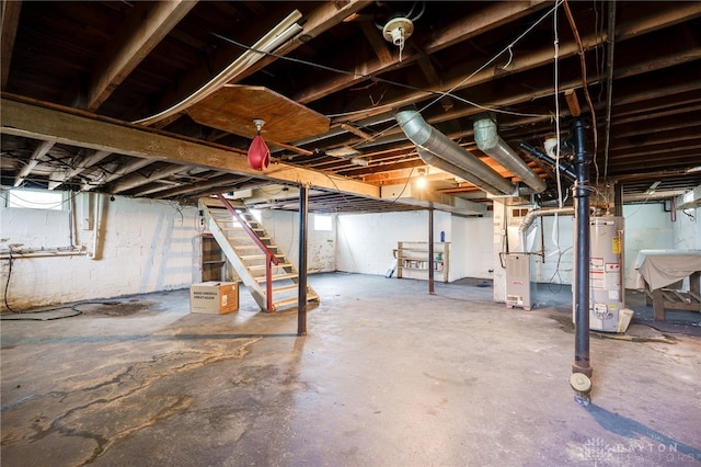 basement featuring heating unit, a sink, stairway, and gas water heater