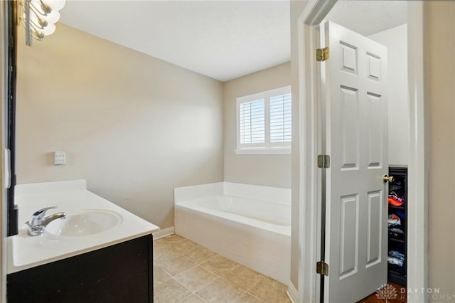 bathroom featuring a garden tub, a sink, baseboards, and tile patterned floors