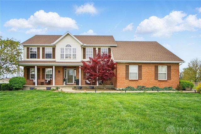 colonial-style house featuring brick siding, a front lawn, and a porch