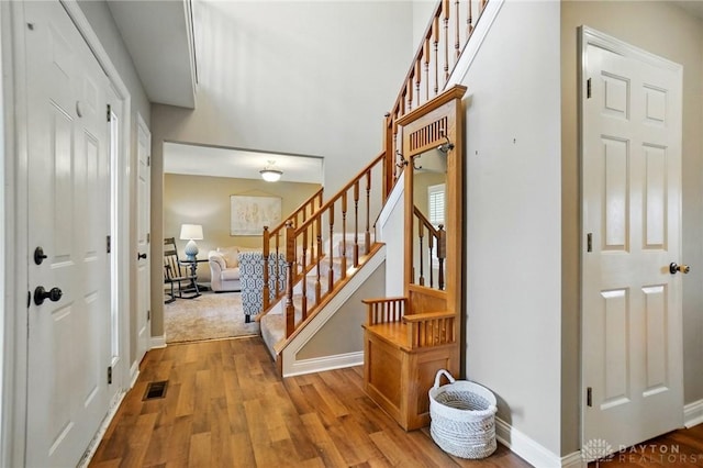 entryway featuring visible vents, baseboards, stairs, and wood finished floors