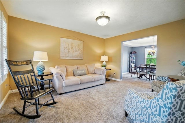 carpeted living room with baseboards and a notable chandelier