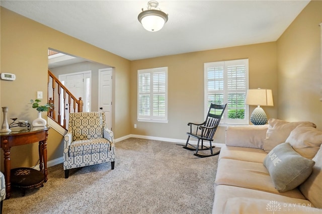 carpeted living room with baseboards and stairs