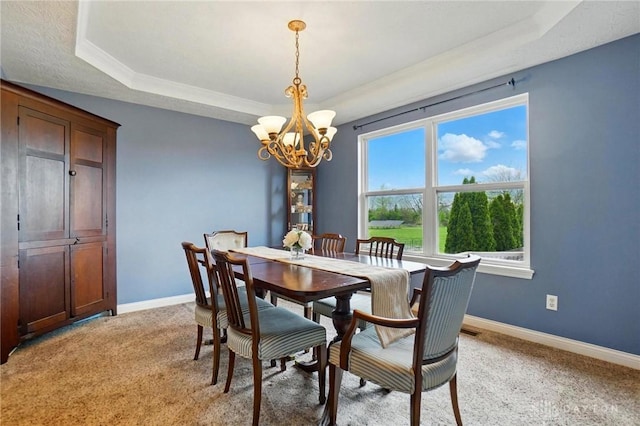 dining space featuring baseboards, an inviting chandelier, and a raised ceiling