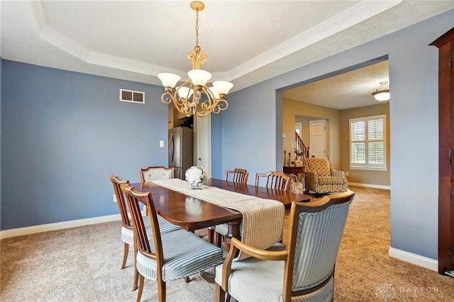 dining space featuring visible vents, a raised ceiling, baseboards, an inviting chandelier, and light carpet