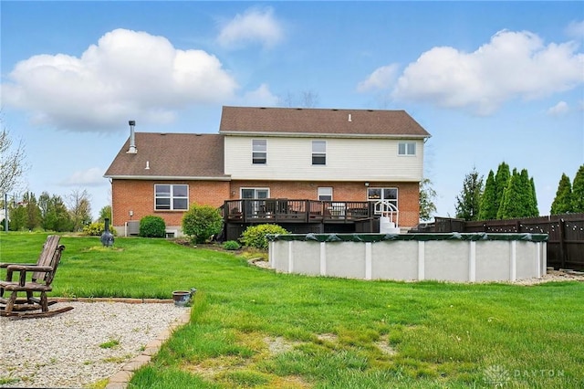 back of property with brick siding, a covered pool, a yard, and a deck