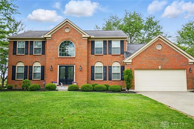 5497 Riverwalk Dr, Kings Mills, OH 45034 - view of front facade featuring french doors, concrete driveway, a front lawn, an attached garage, and brick siding