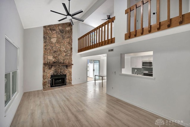 8464 Mcewen Rd, Washington Twp, OH 45458 - unfurnished living room featuring light wood-style floors, high vaulted ceiling, a fireplace, and a ceiling fan