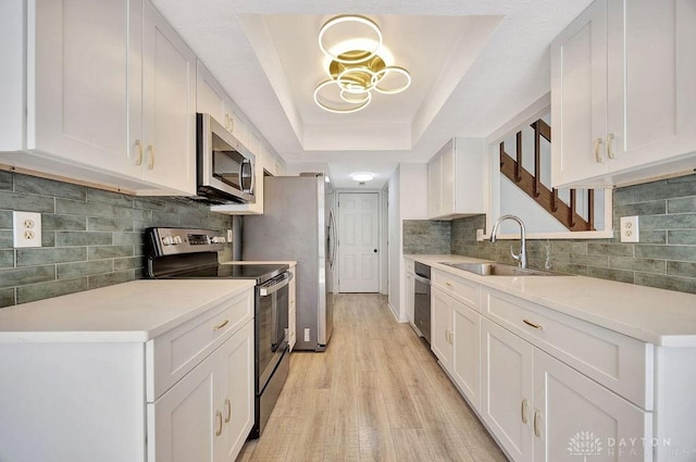 8464 Mcewen Rd, Washington Twp, OH 45458 - kitchen featuring light countertops, a raised ceiling, a sink, light wood finished floors, and stainless steel appliances