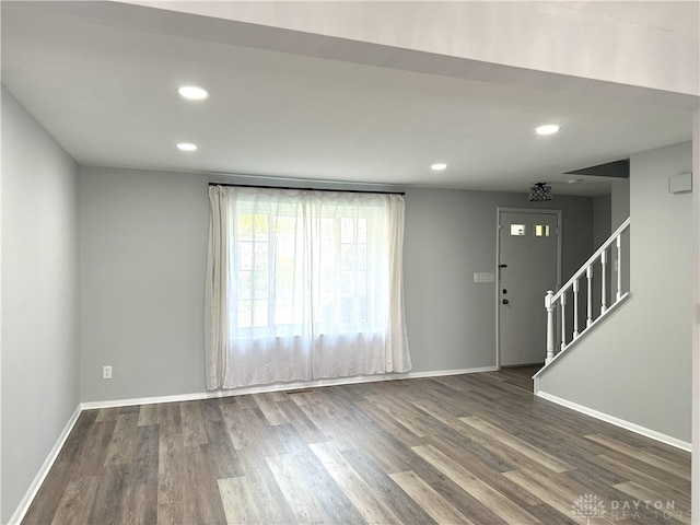 unfurnished living room with baseboards, stairs, and dark wood-type flooring