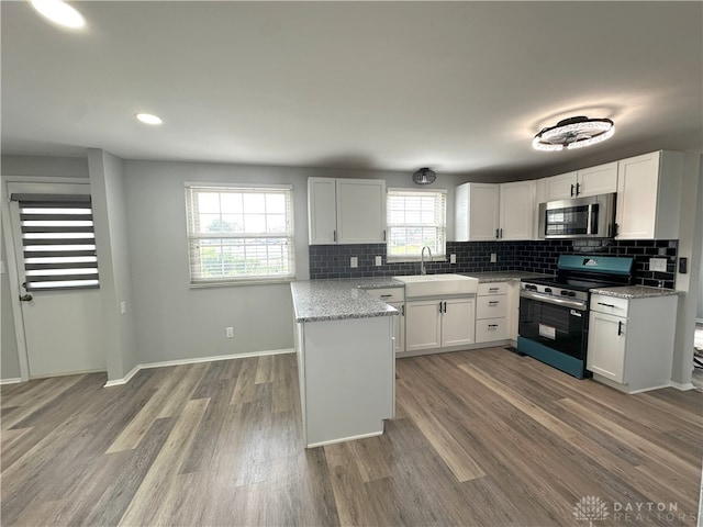 kitchen with backsplash, stainless steel appliances, white cabinets, and a sink
