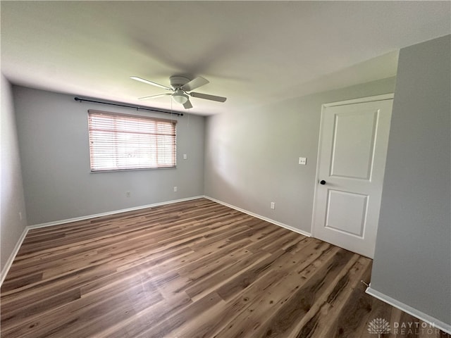 empty room featuring a ceiling fan, baseboards, and wood finished floors