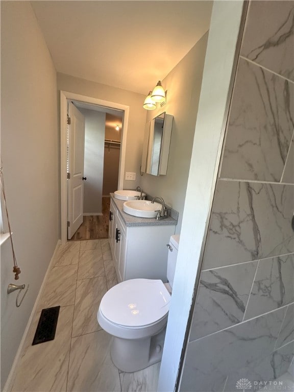 bathroom featuring baseboards, visible vents, marble finish floor, and vanity