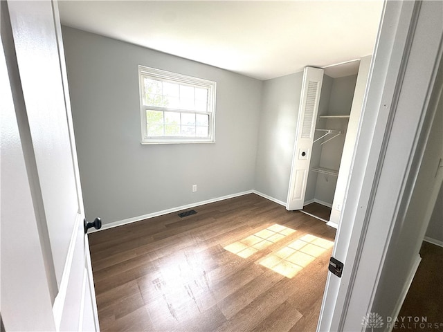 unfurnished bedroom featuring baseboards, visible vents, and wood finished floors