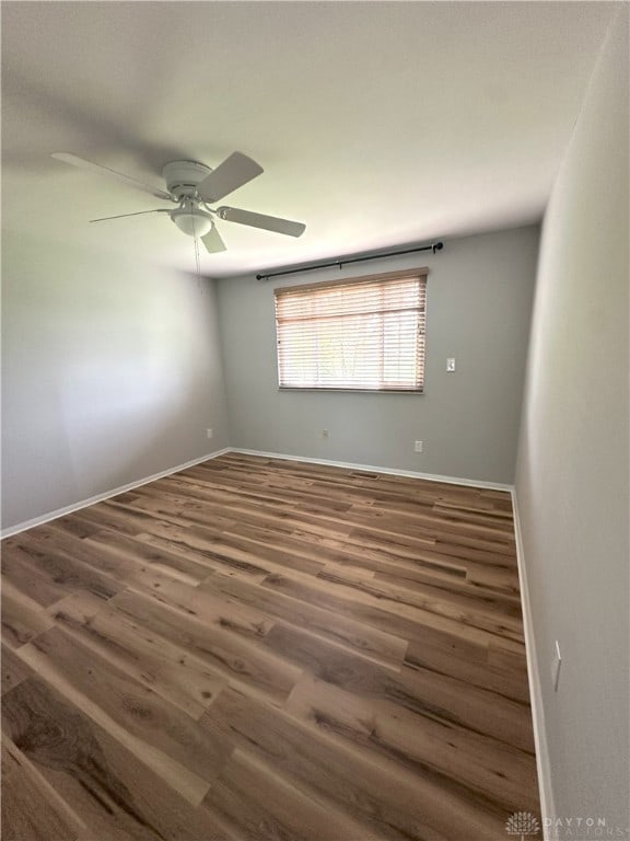 spare room featuring baseboards, a ceiling fan, and wood finished floors