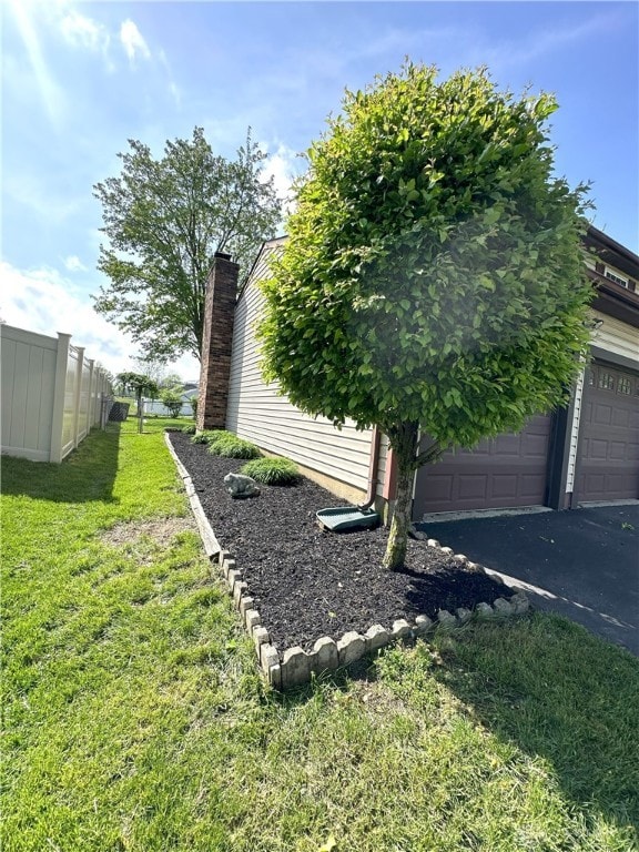 view of yard with a garage, fence, and driveway